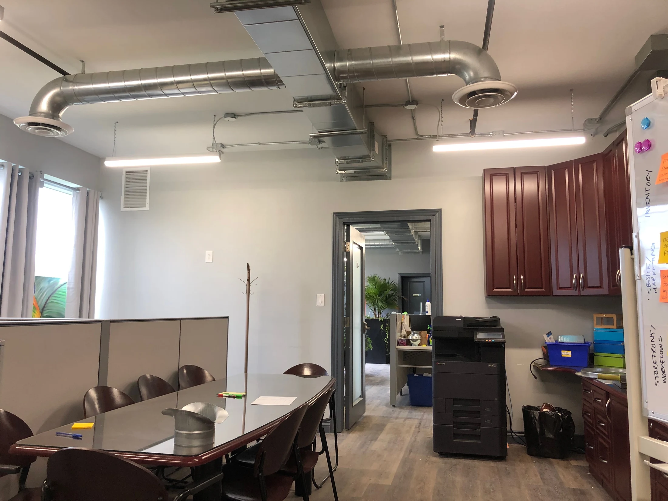 Office meeting area with exposed ductwork, a printer, and a workflow whiteboard
