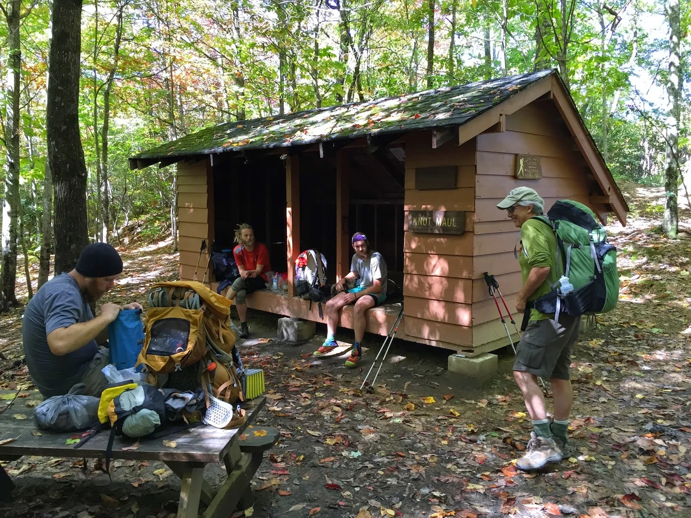 Hikers gathering and resting together outside Knot Maul Shelter in the forest